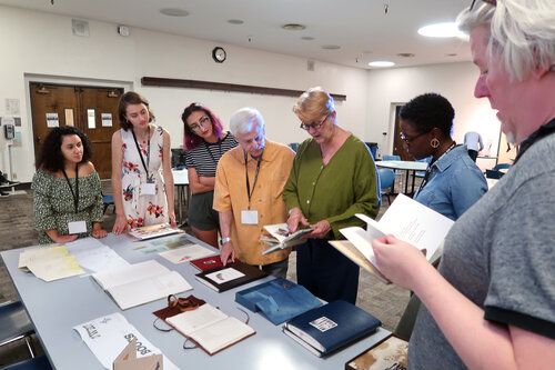 7 people around a table examining notebooks