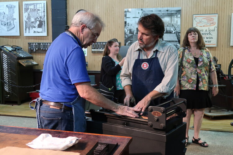 2 men working with an old-style type setting machine