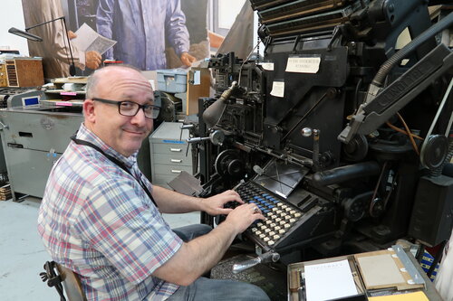 Man sitting at a the keyboard of a Linotype machine